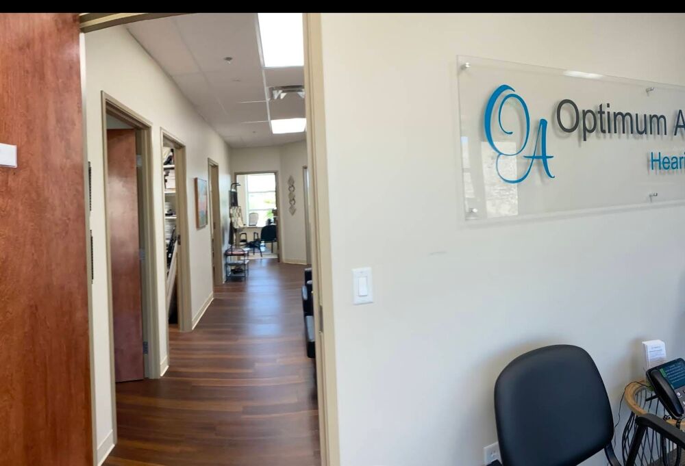 Optimum Audiology logo sign and hallway to patient rooms at the Apple Valley, CA hearing clinic