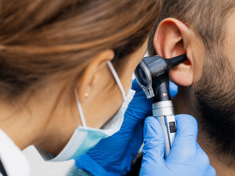 Audiologist examining a patient's ear for occupational hearing loss in the High Desert